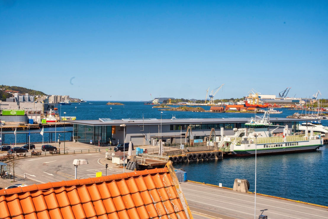 Utsikt over Fiskepirterminalen og havna en solskinnsdag, med en hurtigbåt ved kai